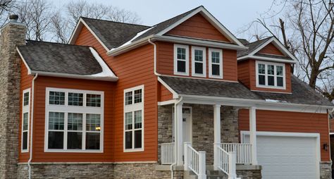 With Rust Colored Siding and a Stone Chimney Orange Siding House, Orange Home Exterior, Rust Exterior House Colors, Rust House Exterior, Rust Color Exterior House Paint, Rust Colored House Exterior, Red House With Stone Accent, Red Siding House Exterior Brown Trim, House With Red Metal Roof