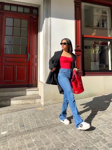 Red top, blue jeans, red bag, city background. Red Bag, Blazer Blue, Red Top, Black Blazer, White Shoes, Black Coat, White Jeans, Blue Jeans, Mom Jeans