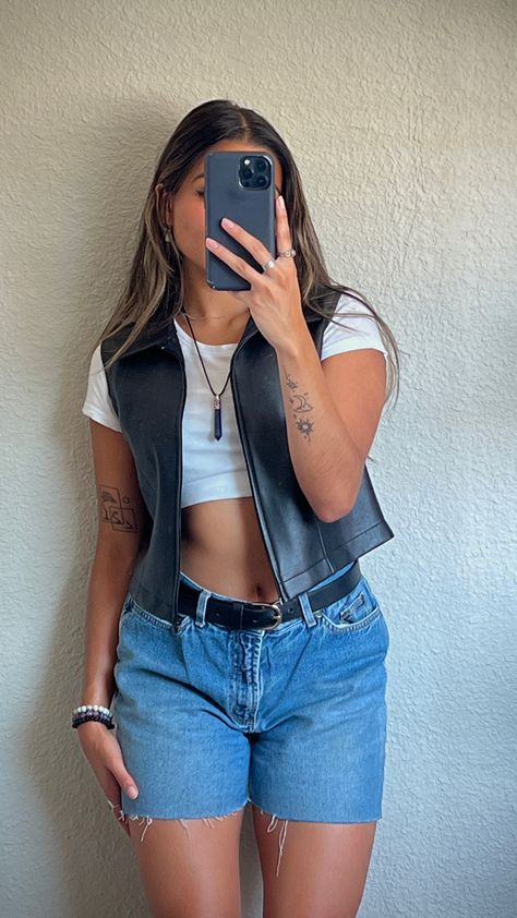 Mirror picture of girl wearing plain white crop top with black leather vest over, jean shorts with black belt, and crystal necklace Cropped Leather Vest Outfit, Vest Outfits Denim, Vest With Tank Top Outfit, Cropped Jean Vest Outfit, Am Concert Outfit, Outfits For The Fair Summer, Black Leather Vest Outfits For Women, Leather Vest Outfit Aesthetic, Button Up Vest Outfits For Women