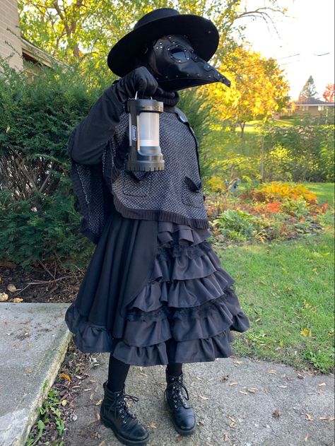 A typical plague doctor costume with a farmer’s hat, a mask with a long beak, long-sleeves tee shirt, a short cape, leather gloves, a (not typical) Lolita-style midi skirt with frills and ruffles, tights, and combat boots. Plague Doctor Inspired Outfits, Crow Mask Plague Doctor, Plauge Doctor Outfits, Plague Nurse Costume, Female Plague Doctor Costume, Plague Doctor Costume Women, Magpie Costume, Plague Doctor Female, Plague Doctor Girl