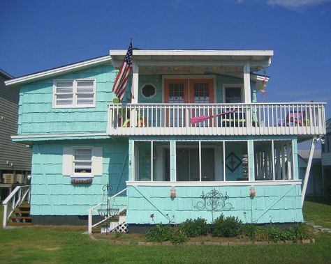 Latitude Adjustment Beach House AFTER  Amazing what a paint job, new railings and a brightly painted French door can do to an awkward 50s beach house. The old fake "half timbered" diagonal braces happily echo the support posts for the top deck, and the bright colors bring some life to the old extra wide corner-wrapped cedar shakes, which are common on mid-century homes. 50s Beach House, 1950s Beach House, Beach House Exterior Colors, 50s Beach, Old Beach House, Painted French Doors, Retro Beach House, 50s House, Beach Shacks