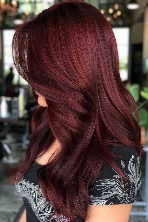 Woman with long, deep burgundy hair styled in soft curls, wearing a patterned black top. Shade Of Red Hair, Cherry Cola Balayage, Brunette Inspiration, Mahogany Highlights, Red Burgundy Hair Color, Maroon Highlights, Dark Cherry Red, Cherry Hair Colors, Red Hairstyles