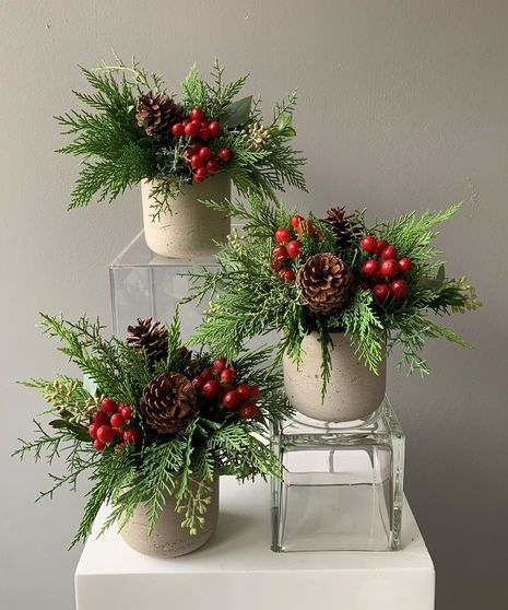 Use a light-colored wooden table or a white tablecloth. Xmas Table Arrangements, Christmas Centerpieces For Work Party, Christmas Flower Arrangements For Table, Floral Christmas Centerpieces For Table, Fancy Christmas Table Decor, Christmas Table Piece, Christmas Party Floral Centerpieces, Christmas Table Floral Arrangements, Mini Christmas Floral Arrangements