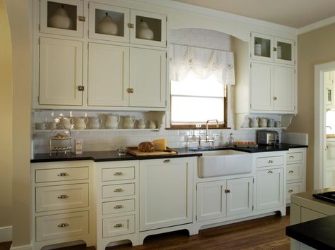 This quaint cottage kitchen features antique white Shaker cabinets, black countertops and a white subway tile backsplash. A white apron-front sink adds a farmhouse-feel to the space. Antique White Kitchen Cabinets, Antique Kitchen Cabinets, Antique White Cabinets, White Kitchen Traditional, Used Kitchen Cabinets, White Shaker Kitchen Cabinets, Antique White Kitchen, Vintage Kitchen Cabinets, Kitchen Cabinets For Sale