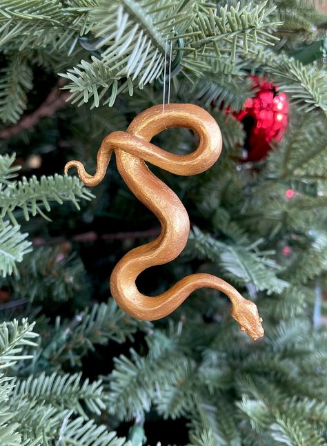 These snake ornaments are cast in hand dyed resin and hand finished/painted.  I sculpted this snake in October 2023 and made a silicone mold of it to cast them in.  You can hang these on a tree, in a window, on a mirror, or just put one on your counter as a unique snake decoration.  They don't just have to be displayed for the holidays.  When these sell I will replace them with new ones.  Colors and finishes will vary.  Please message me with the specific one that you want. Snake Decorations Diy, Snake Decor, Snake Made Out Of Clay, Snake Sculpture, Snake Clay Sculpture, Snake Ceramics, Snake Ornament, Snake Gift, Toy Trees