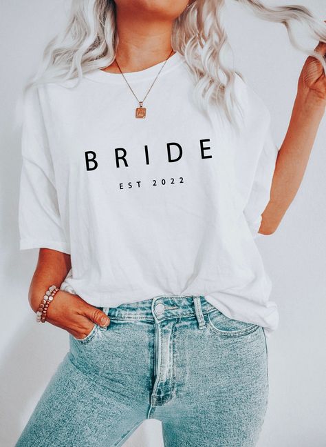 Elevate your bridal style with our Custom Bride Est 2022 T-shirt! Tailored to perfection, it's the perfect gift for every bride-to-be. Crafted with love, it exudes elegance and timeless charm. Embrace your unique journey with this stunning tee that captures the essence of your special day. Stand out and make a statement as you walk down the aisle. A must-have addition to your wedding wardrobe. Shine and create unforgettable memories in style. #BrideToBe #WeddingStyle #UniqueBride Bach Shirt Ideas, Bride Tshirt Ideas, Bride Shirt Ideas, Gifts For New Grandma, Bridesmaid Tshirts, Personalized Bachelorette, Bride Shirt, New Grandma, Bridal Party Shirts