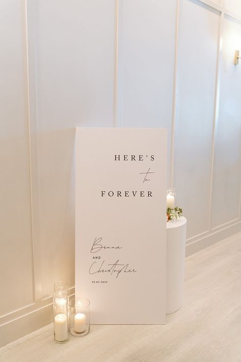 White Here's to forever welcome sign black script Day Of Signage Wedding, Modern Elegant Wedding Signage, Sinages Design For Wedding, Wedding Signage Fonts, Minimalistic Modern Wedding, Welcome Sign To Wedding, Fun Welcome Wedding Signs, Minimal Wedding Sign, Entrance To Wedding Reception