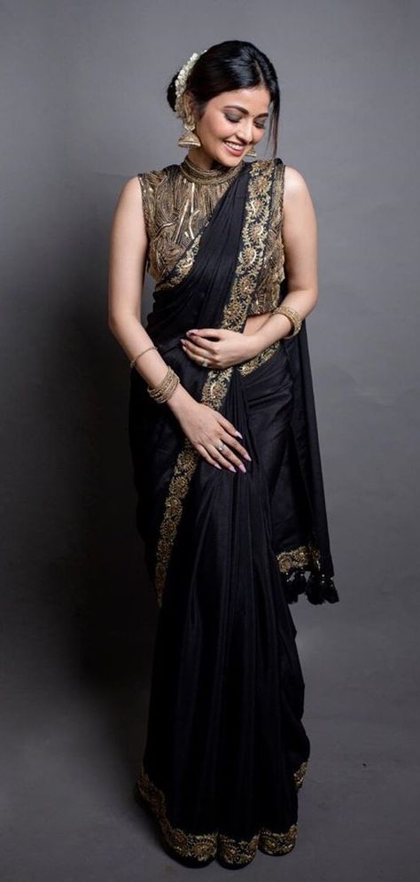 In a gorgeous black & gold color saree and high neck sleeveless blouse design High Neck Sleeveless Blouse Designs, Black Blouse Design, Gold Color Saree, High Neck Saree Blouse, Bridal Outfit Ideas, Chiffon Blouses Designs, Black Blouse Designs, Sleeveless Blouse Designs, Saree Hairstyles