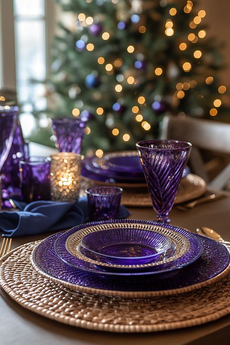 Elegant purple and navy Christmas table setting with wicker, glassware, and a tree in a cozy winter dining room. Christmas Purple Aesthetic, Navy Table Setting, Christmas Table Arrangements, Purple Tablescape, Winter Dining Room, Jewel Tone Color Scheme, Purple Table Settings, Purple Glassware, Navy Table