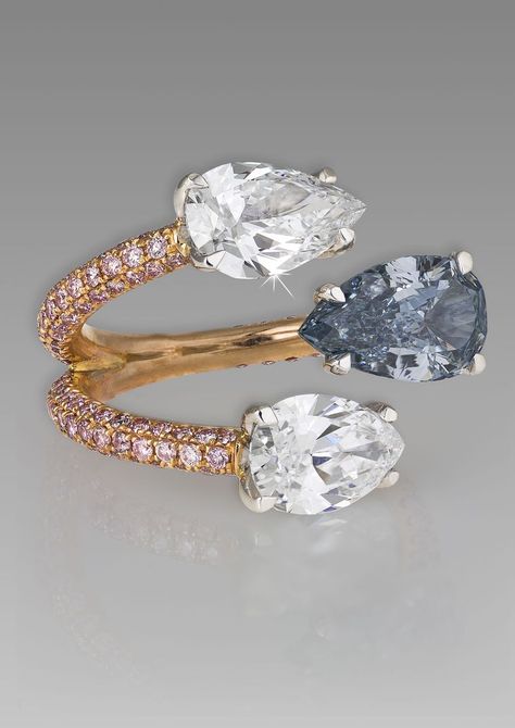 A unique David Morris blue diamond engagement ring featuring a rose gold and melée diamond band that separates to meet two pear-shaped white diamonds and one pear-shaped blue diamond. Two Gemstone Ring, David Morris, Natural Blue Diamond, Blue Diamond Engagement Ring, Cognac Diamonds, Diamond Solitaire Engagement Ring, Unique Engagement, Gems Jewelry, Diamond Band