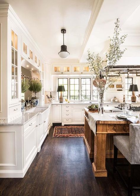 This expansive white and brown kitchen, lit by a Kelly Wearstler Precision Pendant, boasts a large brown wooden island seating black and white stripe counter stools at a wood countertop. French Country Style Kitchen, French Country Kitchen Designs, Rustic Farmhouse Kitchen Cabinets, French Country Decorating Kitchen, Country Kitchen Designs, French Country Design, Farmhouse Kitchen Cabinets, Farmhouse Kitchen Design, Rustic Farmhouse Kitchen