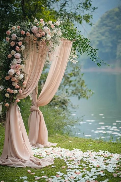 Elegant floral arch with draped fabric by a serene lakeside. Unearth a treasure trove of vibrant and whimsical ideas to sprinkle your spring wedding with the season’s unique charm and charisma. Whimsical Arch Wedding, Whimsical Garden Wedding Theme, Outdoor Wedding Ideas Ceremony, Spring Wedding Decor Ideas, Spring Wedding Decor, Whimsical Theme, Spring Wedding Decorations, Garden Theme Wedding, Rustic Wooden Table