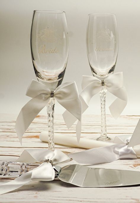 "Our champagne glass set are engraved with the words \"Bride\" and \"Groom\" and they are beautifully adorned with a satin bow with a middle rhinestone charm. They make a great gift to a wedding couple on their special day.  Each champagne glass measures 9 inch tall and can hold about 7oz. The set is shipped securely in a beautiful gift box. We love working with wedding couples, wedding boutiques and wedding creatives. Our main aim is to provide beautifully crafted accessories for the groom and bride on their special day. We ship from Los Angeles, California within 3-5 business days. For expedite shipping, please upgrade to USPS Priority Mail. For questions and more details, please contact us anytime!" Bride And Groom Glasses Champagne Flutes, Wedding Glasses For Bride And Groom, Bride And Groom Champagne Glasses, Aesthetic Champagne, Toasting Glasses Wedding, Wedding Cutlery, Champagne Glasses Wedding, Wedding Toasting Glasses, Bridal Shower Gifts For Bride