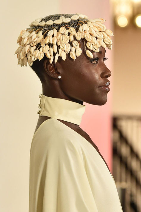 Lupita Nyong'o attended the GO Campaign Annual GO gala looking like royalty with cowrie shells Cowrie Shell Headband, Cowrie Shell Locs, Cowrie Shell Headpiece, Shell Fashion Design, Cowrie Shell Tattoo, Intricate Headpiece, African Headpiece, Shell Headpiece, Afro Jewelry