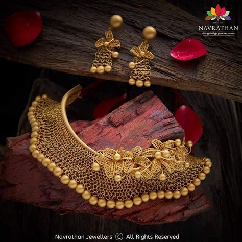 Glittering for your glamour is this choker necklace with glamorous earrings that has beauty in the golden glow of floral petals in lavish gold that merge into sublime bliss in this Mesh Choker, with Golden Petals. Walk in to our stores adorn its aura of beauty and take this Choker Necklace with earrings before it goes off the rack or visit us at www.navrathan.com and get it immediately.  #Jewellery #Navrathan #Jewellers #Gold #Silver #Diamond #GoldNecklaceDesign #SilverArticles #PlatinumJeweller Golden Jwelary Set, Golden Choker Necklace Indian, Golden Jewellery Design, Dubai Gold Jewelry Necklaces Bridal, Golden Necklace Jewellery, Gold Choker Necklace Indian, Navrathan Jewellers, Golden Choker, Glamorous Earrings