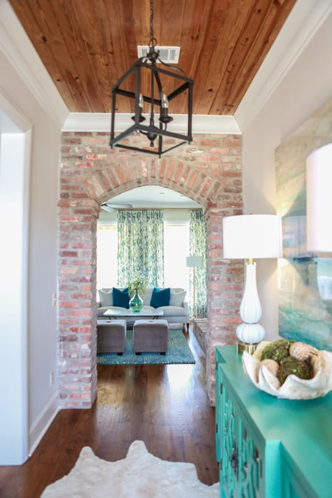 Hallway. Brick wall with arched door. Warm wood ceiling with white trim. Turquoise painted hall table. Lantern pendant. Brick Fireplace Arch, Brick Arch Entryway, Brick Wall Wood Ceiling, Brick Wall Foyer, Arched Brick Entryway, Exposed Brick Entryway, Brick Foyer Entryway, Brick Entryway Wall, Brick Doorway