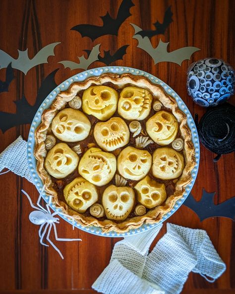 A round apple pie with faces carved into apples on the top. Halloween Apple Pie Ideas, Spooky Apple Pie, Apple Pie Halloween, Skull Apple Pies, Spooky Snack Ideas, Halloween Pie Crust Designs, Halloween Apple Desserts, Creepy Baking, Spooky Bakery