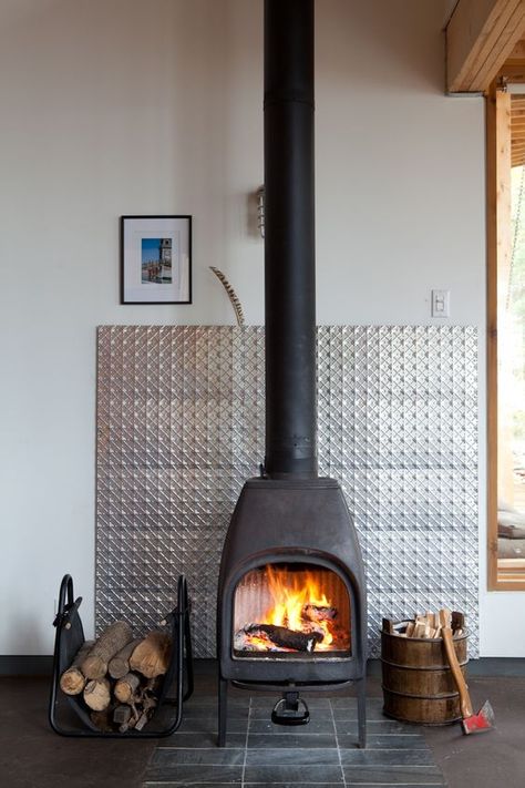 A metal panel protects the wall behind a wood-burning stove and adds a visual focal point within a Canadian vacation home. Photo by: Lorne Bridgman Wood Stove Surround, Modern Wood Burning Stoves, Stove Ideas, Wood Burners, Wood Stove Fireplace, Wood Burning Stoves, Freestanding Fireplace, Fire Places, Stove Fireplace