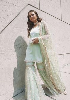 Sharara style is the most #trending outfit this wedding season. The sharara suit is a three-piece outfit which consists of a kurta, #flaredpants and a dupatta. This royal #outfit with a modern twist can take your style statement up a notch. The elegant #sharara is a must-have in every Indian woman’s wardrobe! #traditional outfit #sharara #pastelsuits #indianwedding #indianbride #wedding #bridaloutfit #latestsuits #trendingsuits #trendingsharara #latestsharara #weddingideas #weddinginspiration Sharara Outfit Jwellery, Hand Embroidery On Neck, Wardrobe Traditional, Bridal Dresses 2022, Sharara Suit Designs, Sharara Style, Bridesmaids Outfits, Royal Outfit, Sharara Designs