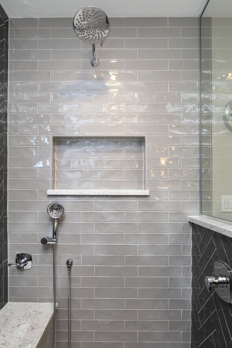 A primary or master bathroom remodeled with a modern/traditional design using shades of grey and off white. Glossy rectangular shower tile set in a herringbone pattern is the statement maker Grey Bathroom Paint, White Shower Tile, Gray Shower Tile, Grey Wall Tiles, Gray Tile, Grey Bathroom Tiles, Shower Wall Tile, Bathroom Shower Walls, Master Bath Ideas