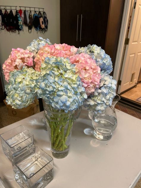 Simple glass vases filled with blue and pink geraniums Hydrangea Gender Reveal, Gender Reveal Flowers Arrangements, Gender Reveal Floral Centerpieces, Pink And Blue Table Decor Gender Reveal, Flowers For Gender Reveal Party, Gender Reveal Floral Arrangements, Gender Reveal Party Flowers, Pink And Blue Graduation Party, Gender Reveal Centerpieces Flowers