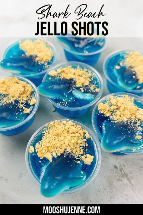 shark coming out of blue jelo with graham cracker crumbs for sand on a concrete board Nautical Themed Alcoholic Drinks, Ocean Jello Shots, Shark Themed Cocktails, Shark Week Drinks Alcohol, Pool Jello Shots, Mermaid Jello Shots, Shark Week Cocktails, Shark Appetizers, Shark Jello Shots