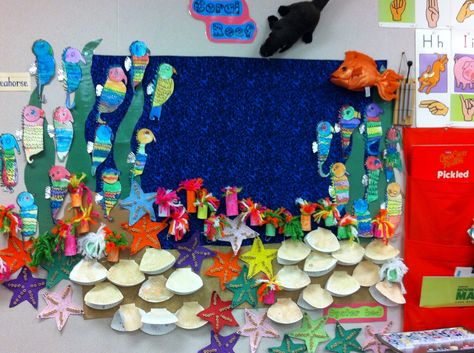 Our Coral Reef bulletin board. Directed drawing sea horses then water colored, sea stars with 5 Cheerios on each ray and counting by 5's, oyster bed with brad pearls and descriptive writing on the inside, sea anemones for dramatic play. Coral Reef Bulletin Board, Great Barrier Reef Craft, Coral Reef School Project, Under The Sea Poster Board, Recycled Coral Reef Art, Coral Reef Recycled Material, Coral Reef Craft, Ocean Bulletin Board, Kids Bulletin Boards