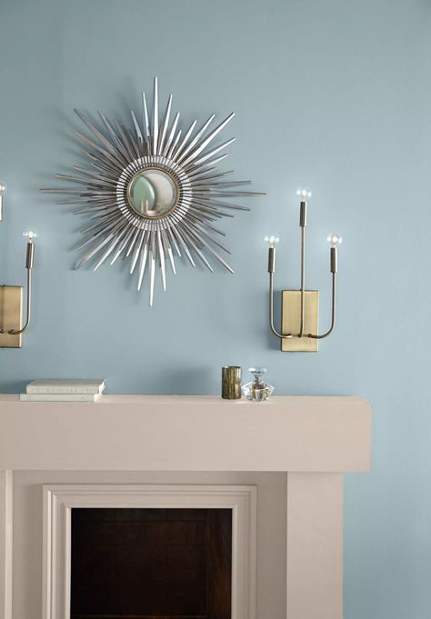 A blue wall painted in a light blue color called Dayflower. A modern fireplace decorated with a chrome sunray mirror and two monumental metal lamps. Dayflower Behr Paint, Behr Blue Grey Paint Colors, Behr Paint Colors Grey, Behr Blue, Behr Color Trends, January Colors, Exterior Gray Paint, Blue Gray Paint Colors, Palette Wall