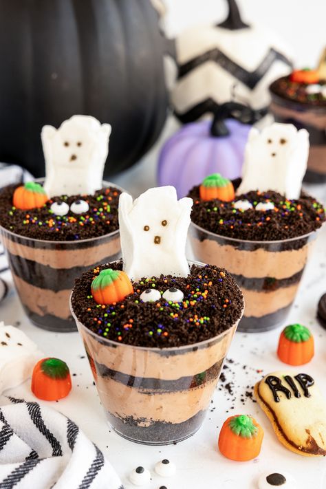 Looking for a spooky, fun, and easy treat to serve at your next Halloween party? These Graveyard Pudding Halloween Dirt Cups are perfect for kids and adults alike! Halloween Treats Dirt Cups, Halloween Pudding Dirt Cups, Dirt Cup Halloween, Pudding Halloween Cups, Halloween Cup Dessert, Halloween Graveyard Dirt Cups, How To Make Dirt Cups, Halloween Dirt Pudding Cups, Spooky Dirt Cups