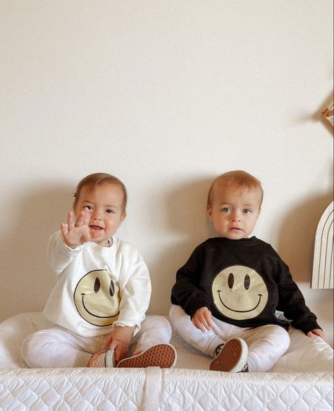 Twins sitting on changing table, both looking at the camera with matching outfits. Girl has a smiley face sweater in color white and boy has the exact same one but in color black. Twins Matching Outfits, Twin Outfits Boy And Girl, Twin Babies Boy And Girl, Boy And Girl Twins, Twin Boy And Girl, Twin Baby Outfits, Twins Boy And Girl, Boy Girl Twin Outfits, Boy Outfits Aesthetic