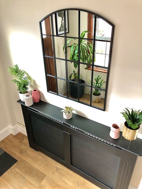 Part of the hallway refurb, I really wanted to cover over the old and tired radiator but felt the a traditional white cover wouldn’t chime with the theme. I found a black version which works really well and allows me to feed my habit of changing up the bits and pieces that sit on top! I’d also coveted this style of window mirror for some time and finally found one in the January sale, it sits opposite a window so bounces the light in this space nicely #hallwaydecor #hallway #hallwayinspo #en Black Metal Console Table, Arched Window Mirror, Entrance Hall Decor, Wood Mirrors, Hallway Mirror, Black Mirror Frame, Black Console Table, Narrow Hallway Decorating, Faux Window