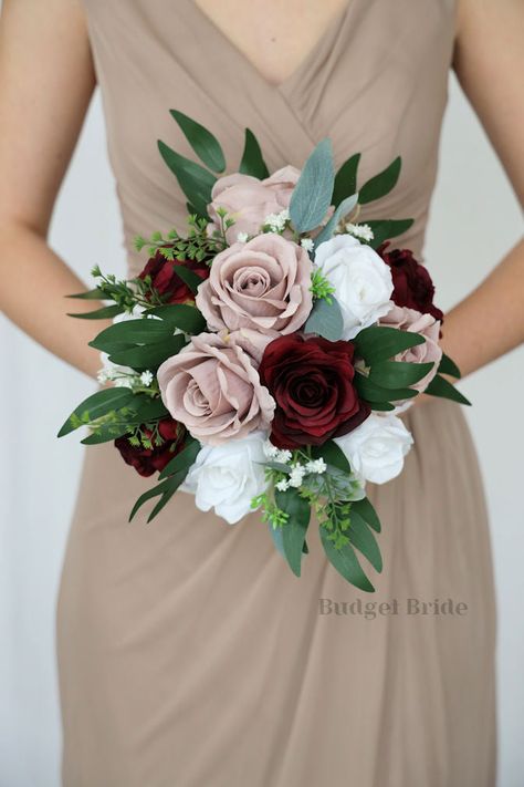 This lovely assortment of burgundy, mauve and white roses is bound to turn heads on your wedding day. This lovely cascading brides’ bouquet from the is an absolutely breathtaking arrangement for any bride to be, in any season. Bright greenery and babies breath complete the look and add a delicate realism to this beautiful bouquet. This bouquet is 10” wide, 18” long, and is crafted by our in-house florists without using a foam base to anchor the flowers to the bouquet. Instead, we wire our bouque Wedding Bouquets Bride Roses, Maroon Flowers Bouquet, Afro Wedding, Burgundy Wedding Bouquet, Small Bridesmaid Bouquets, Fake Wedding Flowers, Sage Eucalyptus, Small Bridal Bouquets, Elegant Wedding Bouquets