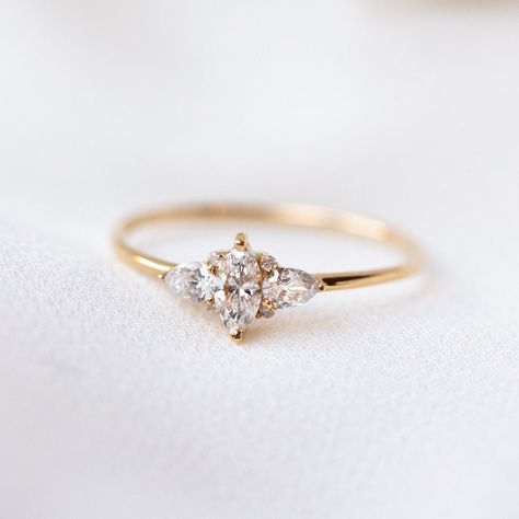 A striking array of diamonds makes this ring sparkle in the light. The 14k Delicate Marquise Cut Diamond Cluster Engagement ring features a marquise cut center diamond surrounded by selection of pear and round cut diamonds. Discover more sustainably sourced engagement rings at Local Eclectic. Delicate Cluster Engagement Ring, Cluster Engagement Ring Round, Simple But Fancy Engagement Rings, Delicate Diamond Engagement Ring, Small Vintage Ring, Minimal Vintage Engagement Ring, Dainty Antique Engagement Rings, Dainty Marquise Ring, Petite Engagement Rings