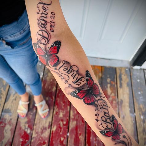 Tattoos For Inner Arm For Women, Red Butterfly Tattoo Forearm, Butterfly With Names Tattoo, Butterfly Tattoo With Name In The Middle, Red Butterfly Tattoo Arm, Butterfly Memorial Tattoo Ideas, Red And Black Butterfly Tattoo, Butterfly Tattoo With Name, Butterfly Memorial Tattoo