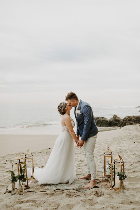 Bride and groom kiss on the beach with lanterns and boho rug in Laguna Beach California #lagunabeachelopement #beachelopement #elopement Elope On The Beach, Beach Elopement Ceremony Set Up, Simple Beach Elopement Ideas, Beach Elopement Ceremony, Boho Beach Elopement, Small Beach Wedding, Dream Elopement, Beach Wedding Locations, How To Dress For A Wedding