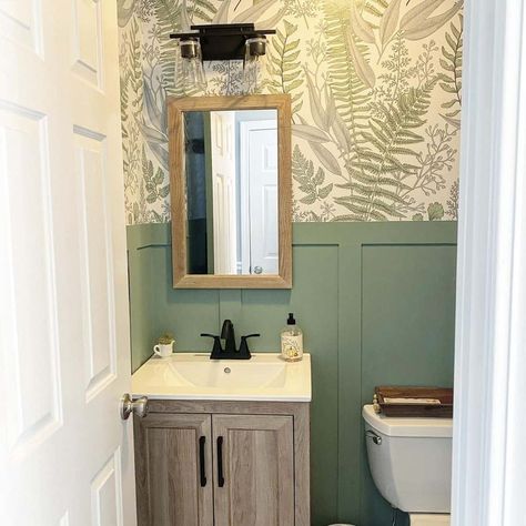 Celebrate forest living by hanging botanical wallpaper above green wainscoting. Use a light wood cabinet with black handles to support the white sink. A wooden tray on the toilet will enhance the forest theme. Small Bathroom Wainscoting Ideas, Light Wood Cabinet, Green Wainscoting, Bathroom Wainscoting Ideas, Bathroom Wainscoting, White Shelving Unit, Gray Bathroom Walls, Forest Living, Light Grey Bathrooms