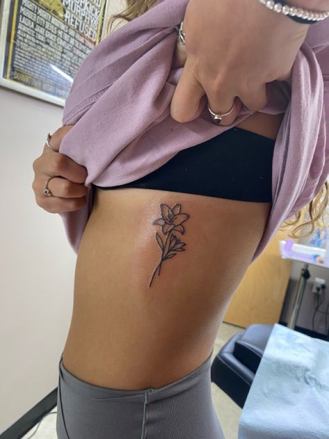 Tiny Lily Flower Tattoo, Lily Flower Rib Tattoo, Tattoo Ideas Female Lily Flower, Lower Side Stomach Tattoos Women, Lillies Tattoo Designs, Lilly Name Tattoo, Flower Bouquet Tattoo Hip, Daylillies Tattoos, Tattoo Of Lily Flower