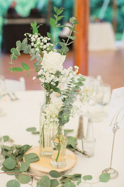 Small Flower Arrangements With Eucalyptus, Eucalyptus Flower Centerpiece, Sage Green And White Centerpieces, Clear Bottle Centerpieces, Small White And Greenery Centerpiece, Bud Vases With Eucalyptus, Simple Sage Green Wedding Decorations, Simple Green And White Centerpieces, Simple Green Centerpiece Wedding