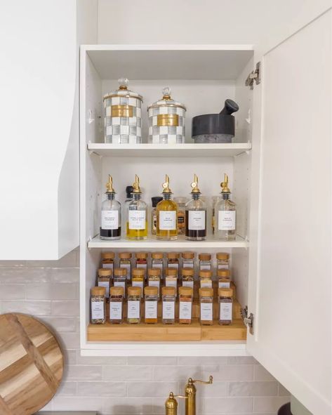 We just did a spice cabinet makeover and I love how it turned out. We bought a wood spice rack, spice jars with wood lids, gold bottle dispenser, and beautiful checked canisters. Click the link to find out where we bought them! Spice Jars With Wood Lids, Spice Organizer For Cupboard, Gold Spice Jars, Spices Organization Cabinet, Upper Spice Cabinet, Kitchen Spices Storage Ideas, Spice Jar Organization, Pawson House, Apartment Manifestation