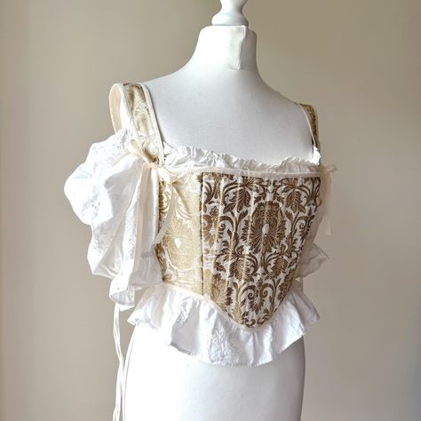 Handmade corset / stays made from a gold and ivory brocade, with coutil interlining, and a satin lining, and gold eyelets. The stays are finished with extreme care to detail with ribbon lacing, metal eyelets, and cotton binding. Fully boned with 19 pieces of plastic boning. Size is around a Small - flexible due to the lace up back. The mannequin it's shown on is a 32" bust and a 26" waist, and flat lay measurements when completely closed (so the smallest size I'd recommend it for) is 15" across White And Gold Corset, Rococo Fashion 18th Century, Rococo Clothing, Fantasy Corset, Corset Stays, Pirate Corset, Handmade Corset, Brocade Corset, Gold Corset