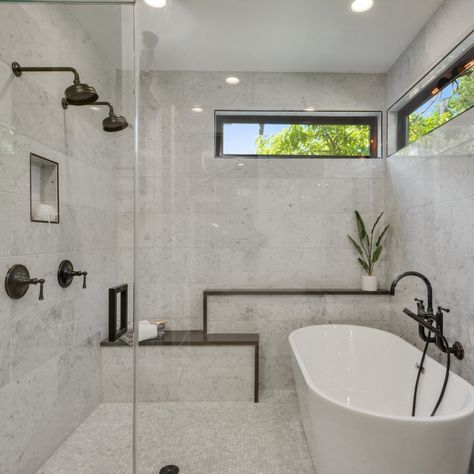 There's so much to love about this bathroom. Placing the bathtub inside the shower is a stylish space saver that also waterproofs the whole bathroom. Double shower heads make this an easy space to share. The cool stone is a perfect touch with a natural looking bench built in. Natural light from the clerestory windows keeps the space feeling bright and open while maintaining privacy. And last but not least, industrial accents add the perfect amount of modern edge! #kelleydesigngroup #bathroom Shower In Tub Combo, Modern Shower Tub Combo Master Bath, Bathroom With Bathtub And Shower Layout, Shower Bathtub Combo Layout, Walkin Shower With Bathtub, Master Bath Tub Shower Combo, Soaker Tub Shower Combo Small Bathrooms, Modern Shower Tub Combo, Bath Tub Inside Shower Area