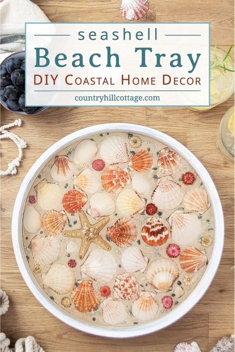 How to make a modern round wood DIY beach tray with seashells! The easy seashell craft is a fun summer craft project and rustic farmhouse coastal decor. The step-by-step makeover tutorial includes ideas for materials and working with epoxy resin to create a homemade white painted wooden seashell serving tray with gold trim! Elegant as living room decor, coffee table centerpiece, kitchen display, custom tea tablet, or outdoor party. #servingtray #tray #homedecor #coastal| CountryHillCottage.com Epoxy Resin Seashell Table, Seashell Display Coffee Table, Seashell Epoxy Table, Fast Diy Crafts, Seashell Coffee Table, Shells Diy Decoration, Epoxy Resin And Sea Shells, Resin Crafts With Seashells, Crafts To Do On The Beach