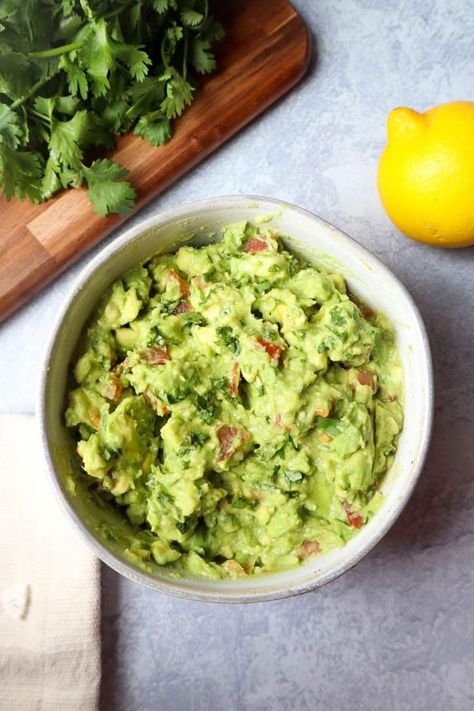 white bowl with guacamole without onion, side of cilantro and lemon juice