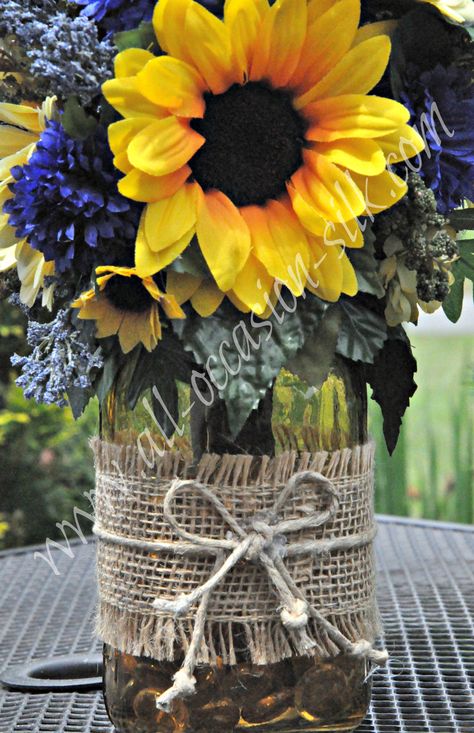 Rustic-style centerpiece featuring sunflowers, blue delphinium, blue pom poms, and gerbera daisies in a yellow-tinted mason jar tied with burlap and twine Tinted Mason Jars, Blue Pom Poms, Sunflower Wedding Decorations, Sunflower Centerpieces, Sunflower Arrangements, Blue Delphinium, Deco Nature, Gerbera Daisy, Yellow Wedding