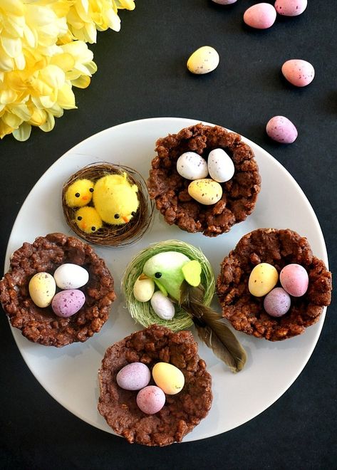 Overhead shot of a white plate with 4 rice krispies nests and 2 bird nests, mini Cadbury eggs and flowers around the plate Easter Egg Rice Crispy Treats, Easter Nests Recipe, Rice Krispie Nests, Easter Rice Krispie Treats, Easter Egg Nest, Chocolate Rice Krispies, Easy Easter Treats, Easter Nests, Easter Dishes