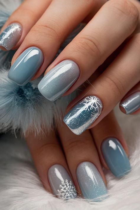 These nails capture the essence of winter with a stunning blue gradient, delicate snowflake designs, and a touch of glitter. The smooth transition from light to dark blue creates a frosty effect, making this design perfect for embracing the winter season. The glossy finish and intricate details add elegance, making it ideal for both casual and special occasions. Winter Round Nails, Blue Snowflake Nails, Winter Blue Nails, Christmas Winter Nails, Glitter Christmas Nails, Blue Winter Nails, Nails Navy, Winter Nail Art Designs, Year Nails