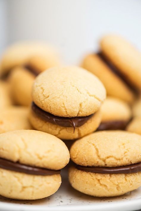 Have you ever tasted baci de dama? These mini Italian chocolate filled sandwich cookies are made with chocolate and vanilla. One or two of these Italian cookies with chocolate in the middle will definitely put a smile on your face. The buttery vanilla cookies are sandwiched together with chocolate so you can enjoy both flavors in every bite. This version of these chocolate filled cookies is made without hazelnuts. Baci di dama are mini Italian chocolate sandwich cookies. #cookies #italian Afternoon Tea Party Food, Tea Party Food Ideas, C Is For Cookie, Tea Party Menu, Red Wine Sangria, Cookie Sandwich Recipes, Amaretti Cookies, Wine Sangria, Italian Chocolate