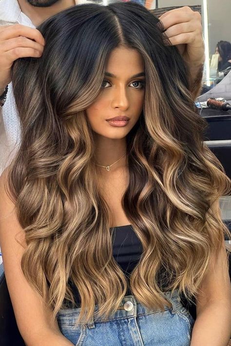 Long voluminous waves with a center part, blending black hair with rich caramel balayage. The cascading curls add depth and movement, enhancing the multi-tonal effect for a glamorous look.  // Photo Credit: Instagram @solotreartofbeauty Caramel Balayage For Black Hair, Caramel Hair Balayage Honey, Caramel Balayage Dark Roots, Dark Brown Hair With Caramel And Blonde Highlights, Light Caramel Highlights On Black Hair, Dark Long Hair Balayage, Black With Caramel Balayage, Baliage Hair Fall, Dark Blonde Balayage Long Hair