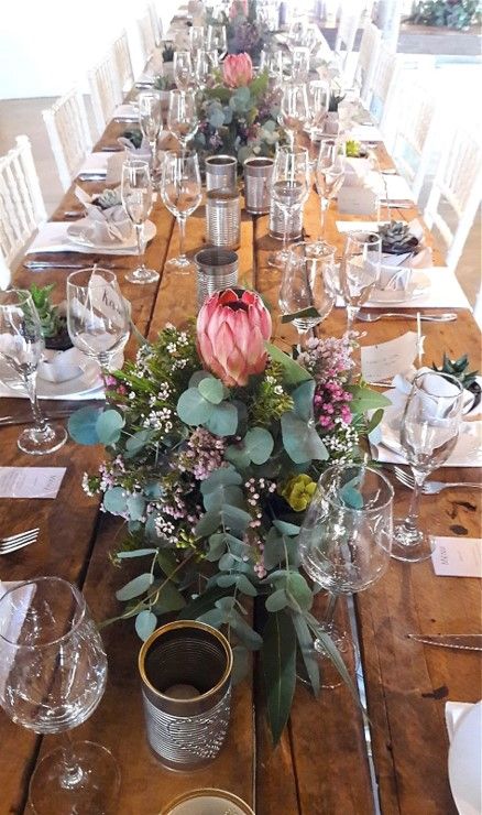 This style of table decor is so popular and looks so beautiful in the form of a table runner. It includes a range of different varieties of proteas, fynbos and greens in separate trays.  #Fynbos #Spring #Flowers #FabulousFynbos Protea Themed Wedding, Botanical Wedding Table Decor, Protea Table Decor, Protea Wedding Table Decor, Protea Flower Arrangements, Fynbos Wedding, Fall Wedding Place Settings, Protea Wedding, Table Arrangements Wedding