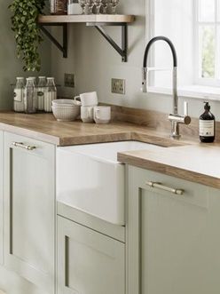 Pale enough to work as a neutral, the sage green tone of these sturdy, 20mm-thick doors makes a great choice for those that want a subtle style with plenty of country character. Choose from a wide variety of cupboards, such as larder units, which can keep cooling devices hidden from view to help maintain an uninterrupted design. Light Kitchen Cupboards, Kitchen Pale Green, Howdens Elmbridge Sage Green, Country Kitchen Colour Schemes, Sage Green Vintage Kitchen, Heritage Sage Kitchen, Japandi Kitchen Sage Green, Small Sage Kitchen Ideas, Olive Green Country Kitchen